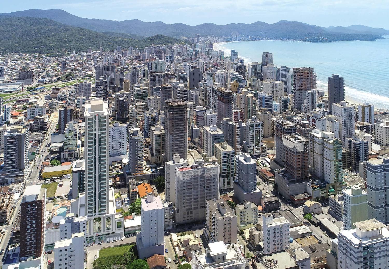 Vista aérea da Meia Praia mostrando a torre do Ametista Home Club e o mar de Itapema