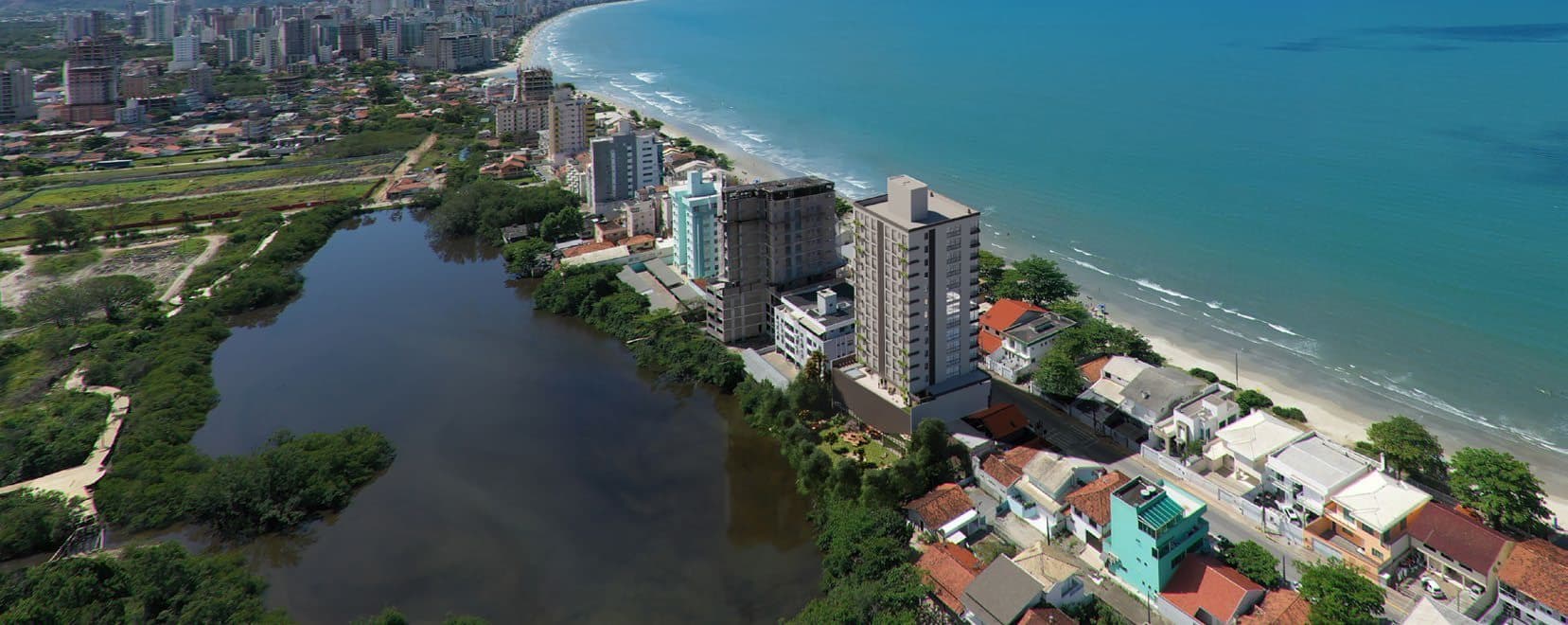 Vista aérea do Balneário Perequê mostrando a Lagoa do Perequê e o mar, onde fica o Amrita Apartments