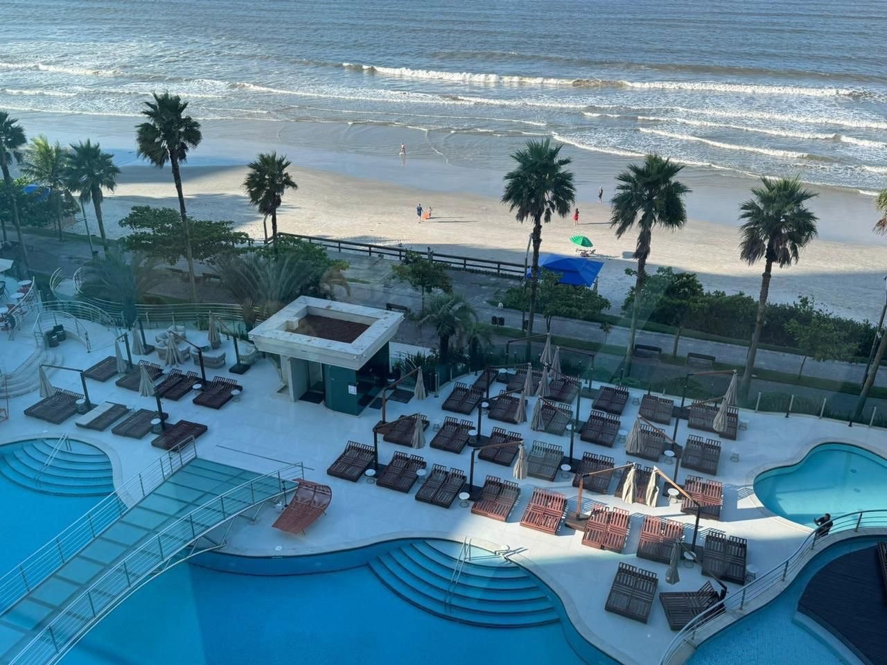 Vista de dentro de um apartamento do Atlantic Paradise Towers para as piscinas do condomínio e a praia de Meia Praia, em Itapema