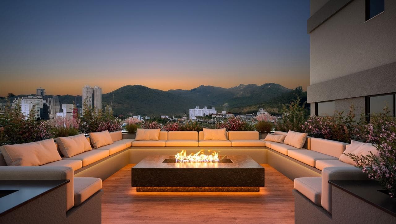 Fire place do Riviera Home Club ao anoitecer, com sofás em volta da lareira