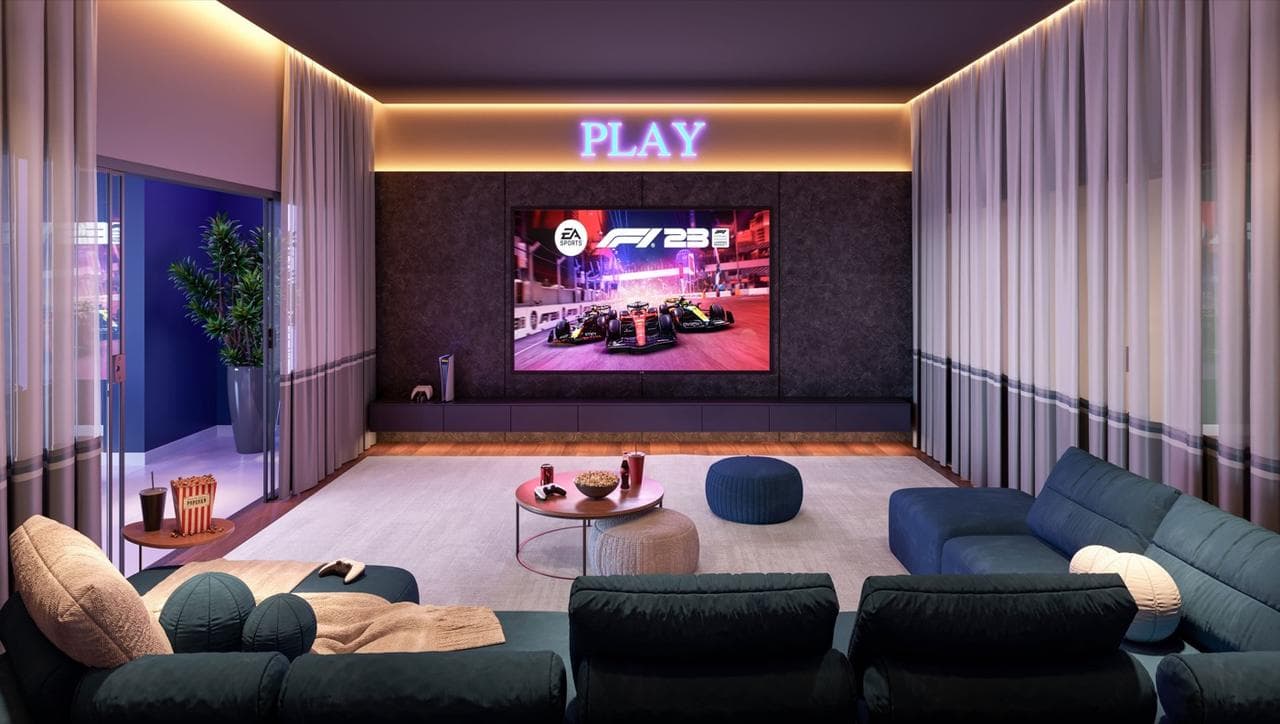 Sala de TV e games do Riviera Home Club, com telão e sofás