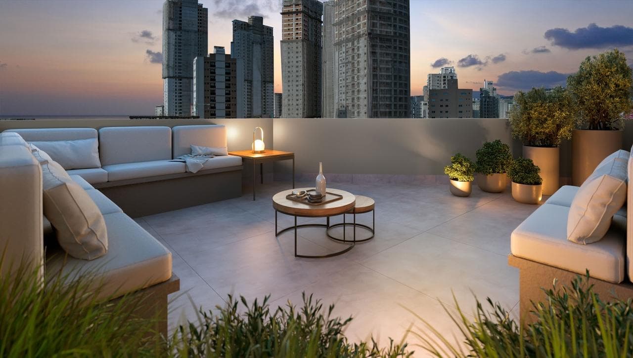Terraço externo do Riviera Home Club, com sofás e vista para os prédios de Itapema